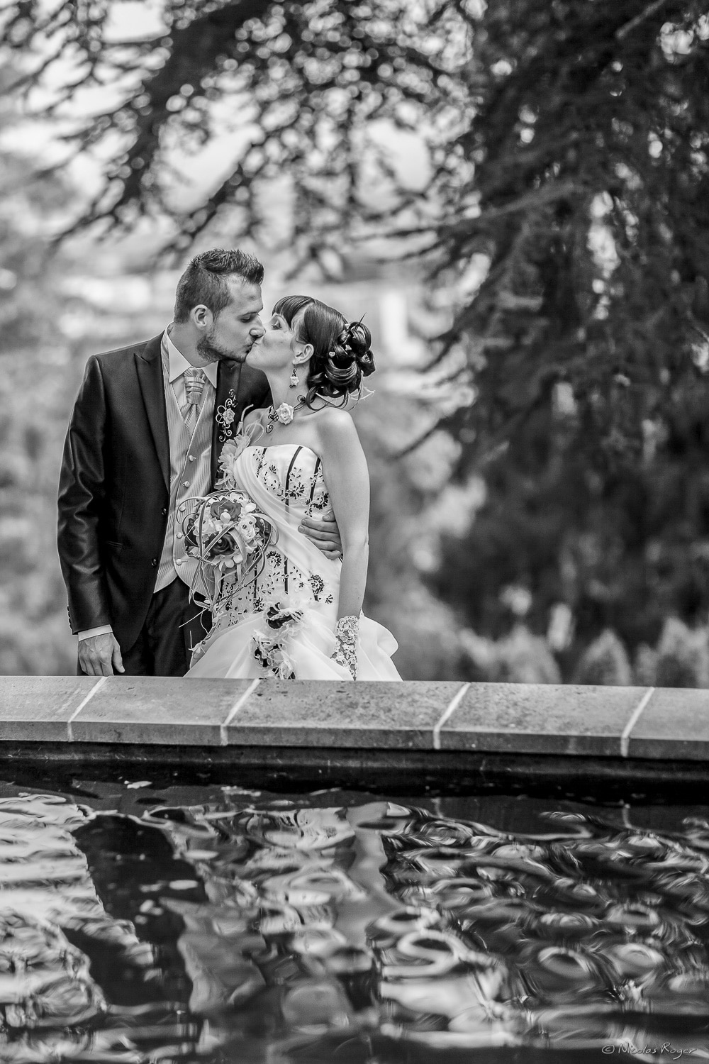 Baiser des mariés devant un bassin