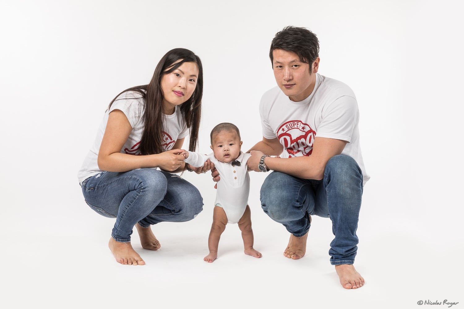 Photographie d&rsquo;un couple avec leur enfant qu&rsquo;ils font tenir debout.