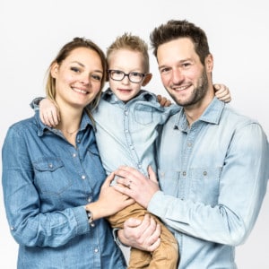 Photographie d'une famille avec leur jeune enfant dans les bras.