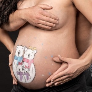 Photographie d'un couple autour d'un belly painting sur le ventre de la femme enceinte.