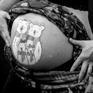 Photographie de grossesse avec un belly painting qui représente la famille.