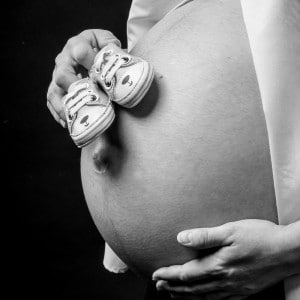 Photographie de grossesse avec les chaussons du futur bébé.