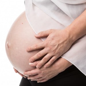 Photographie de grossesse avec les mains du couple sur le ventre.