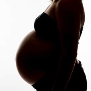 Photographie d'un profil d'une femme enceinte dans l'ombre