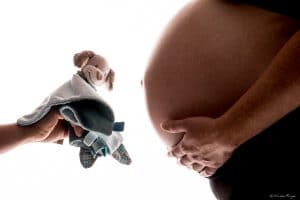 Photographie d'un ventre de femme enceinte avec le futur doudou de l'enfant