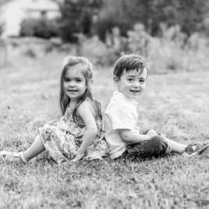 Image d'un frère et une soeur dos à dos dans un jardin.