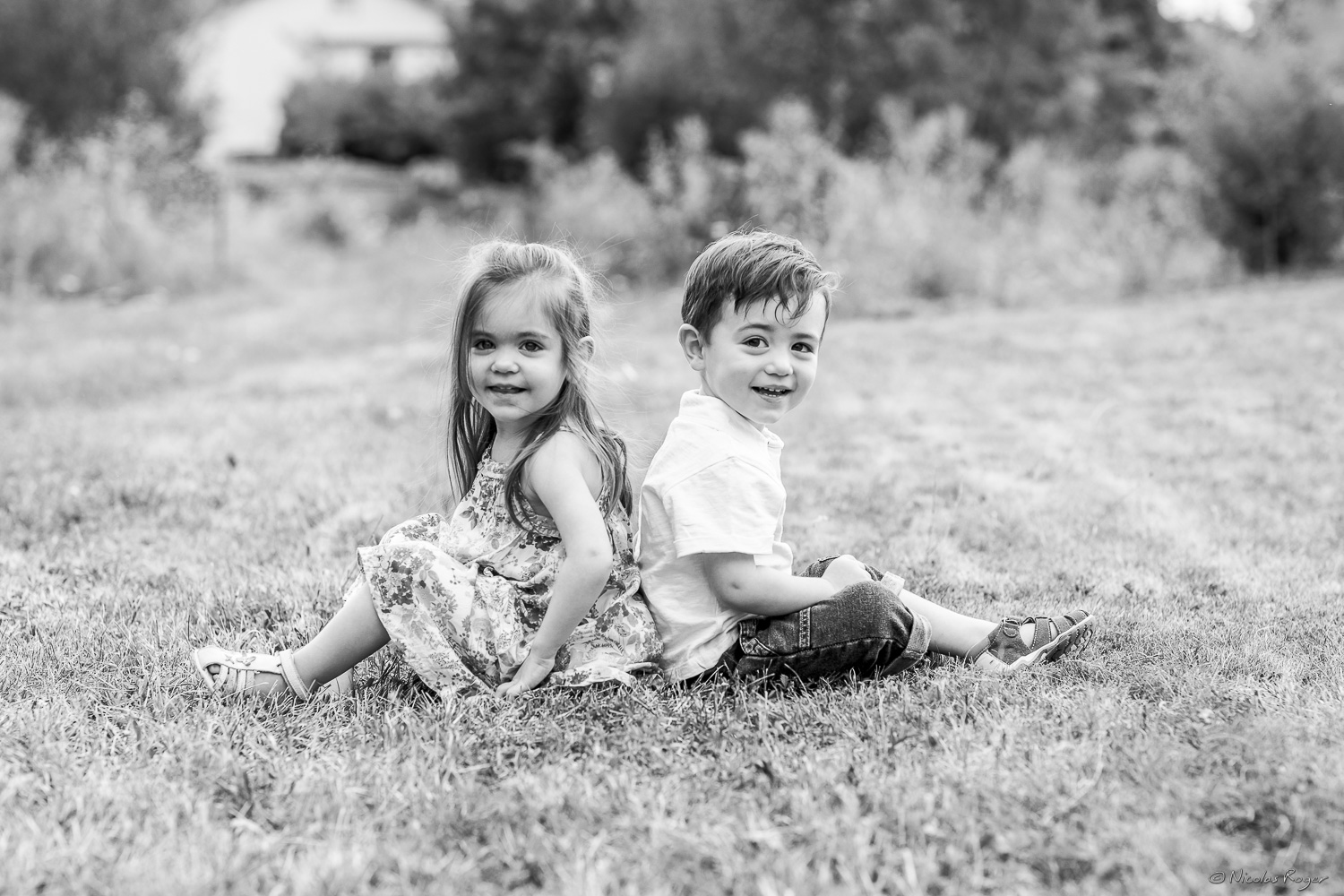 Image d&rsquo;un frère et une soeur dos à dos dans un jardin.