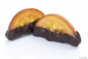 Photographie de quartiers d'orange en partie trempés dans le chocolat